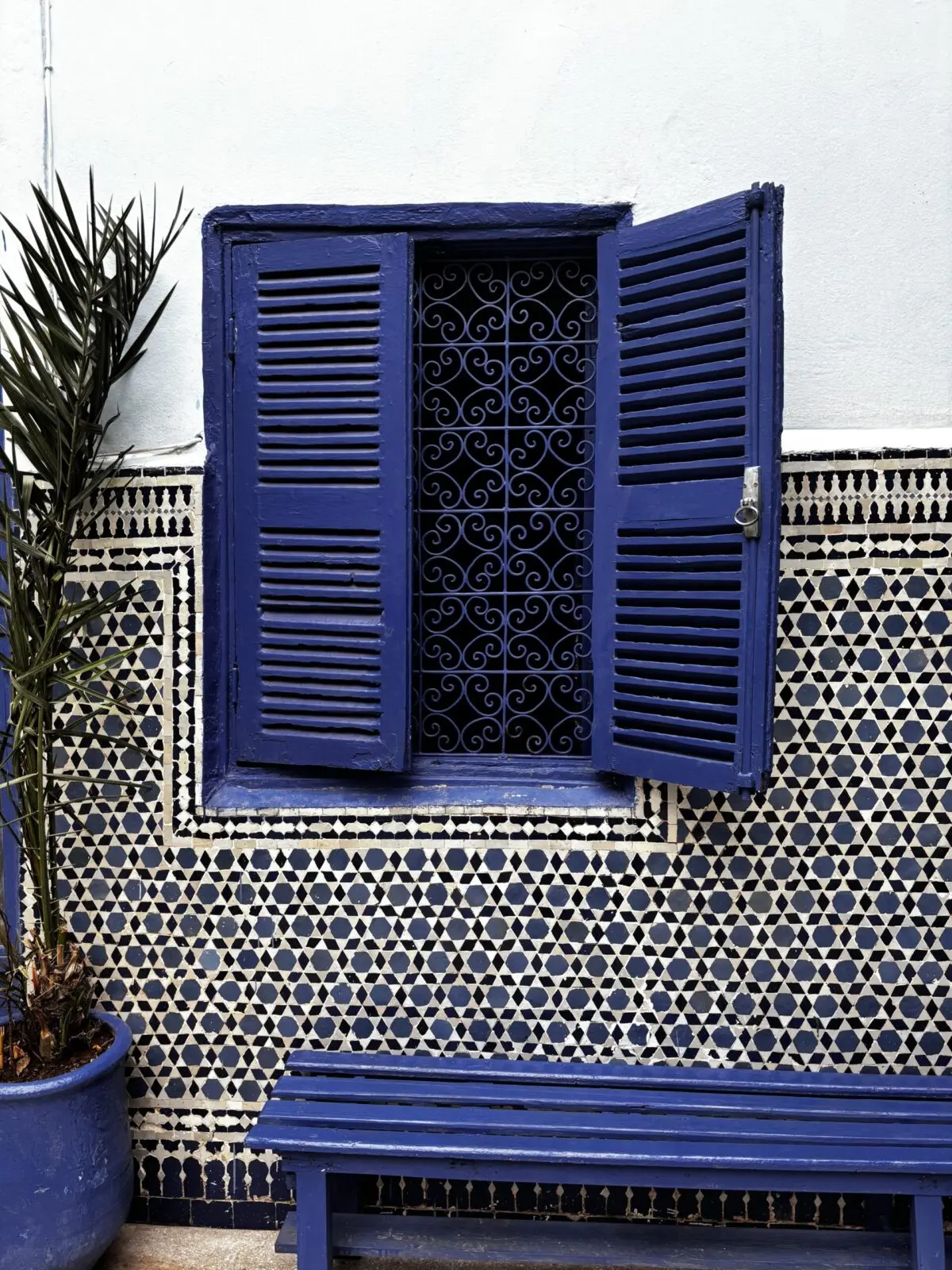 Blue window in tiled wall, with a bright blue bench underneath 