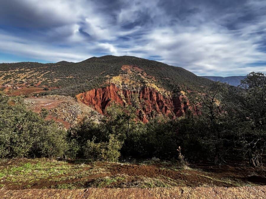 Colourful mountain scenery with red cliffs and green vegetation, perfect for travel enthusiasts.