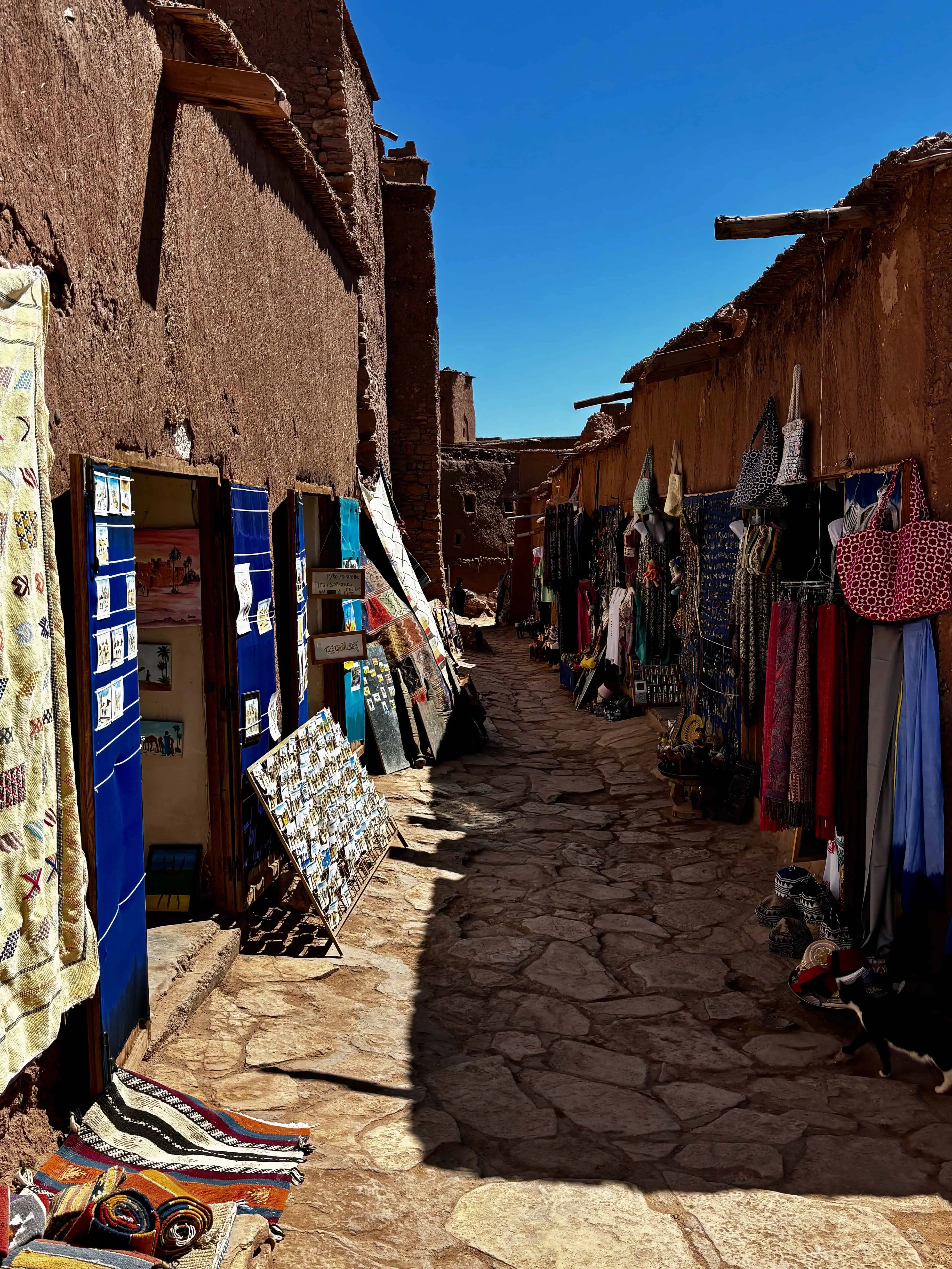 Traditional Moroccan market street with colourful textiles and souvenirs in an old desert village.