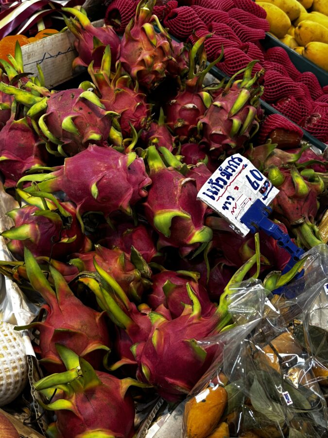 Exotic fruit in deep reds, close-up, with Thai sign