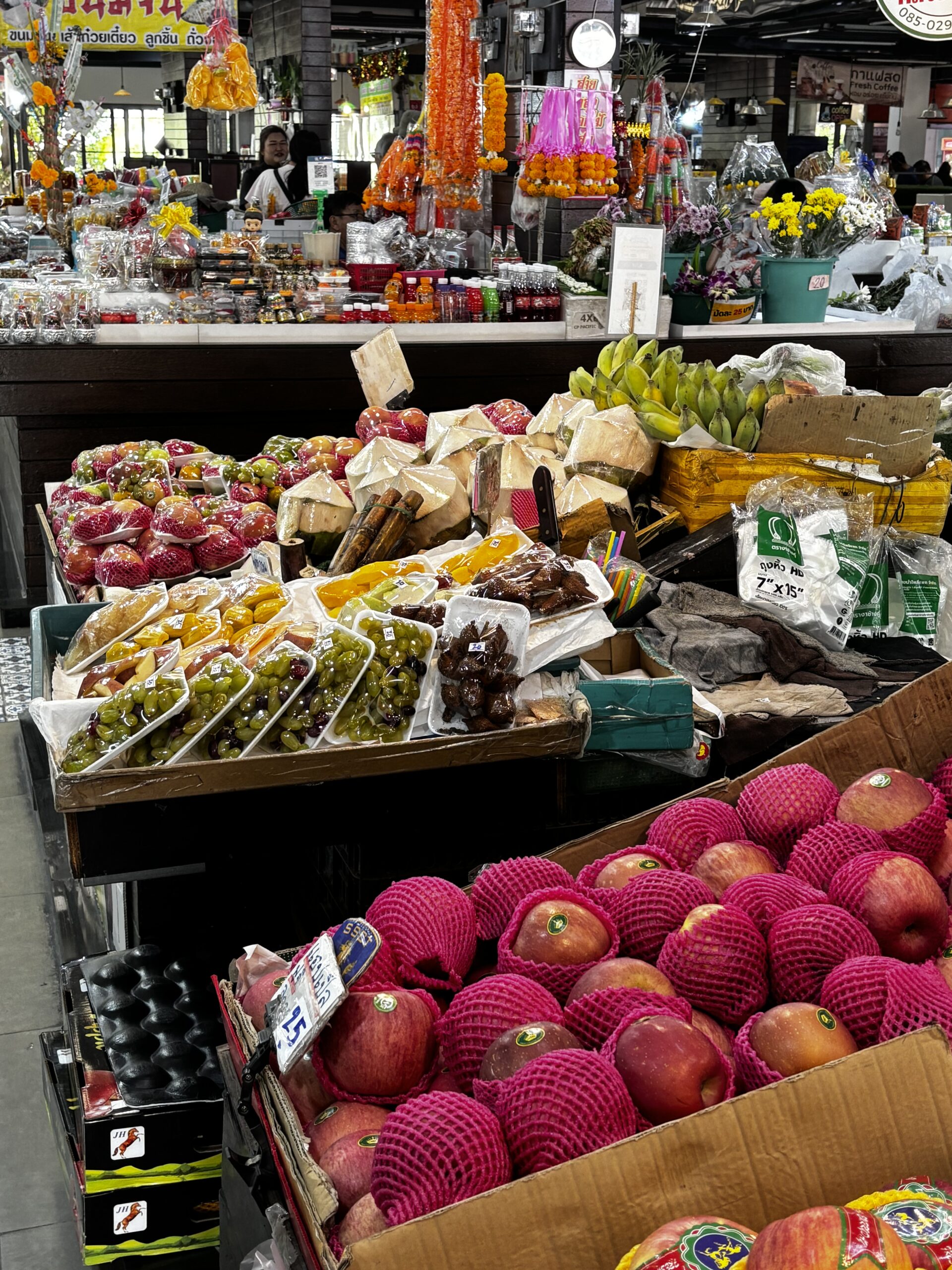 Fruit and vegetables at a Thai market on the way to a cooking class and a smiling Thai woman in the background.