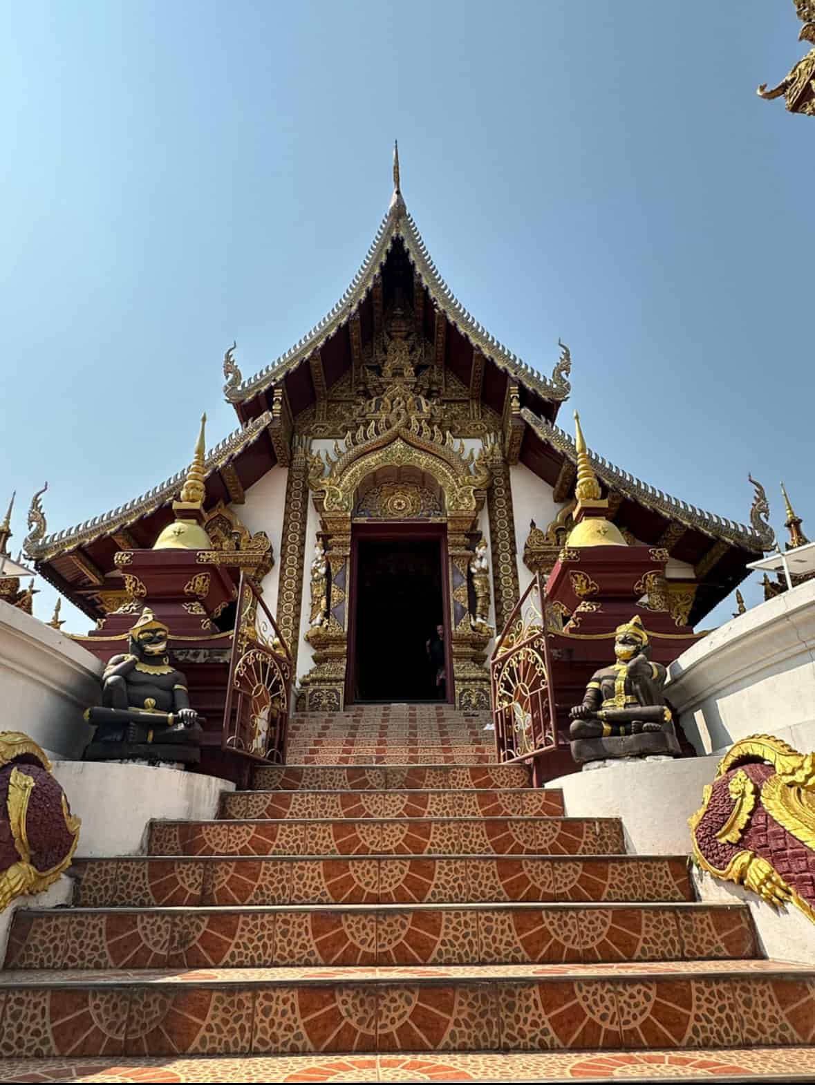 Flight of stairs leading up to a temple with gold and wood, in Bangkok