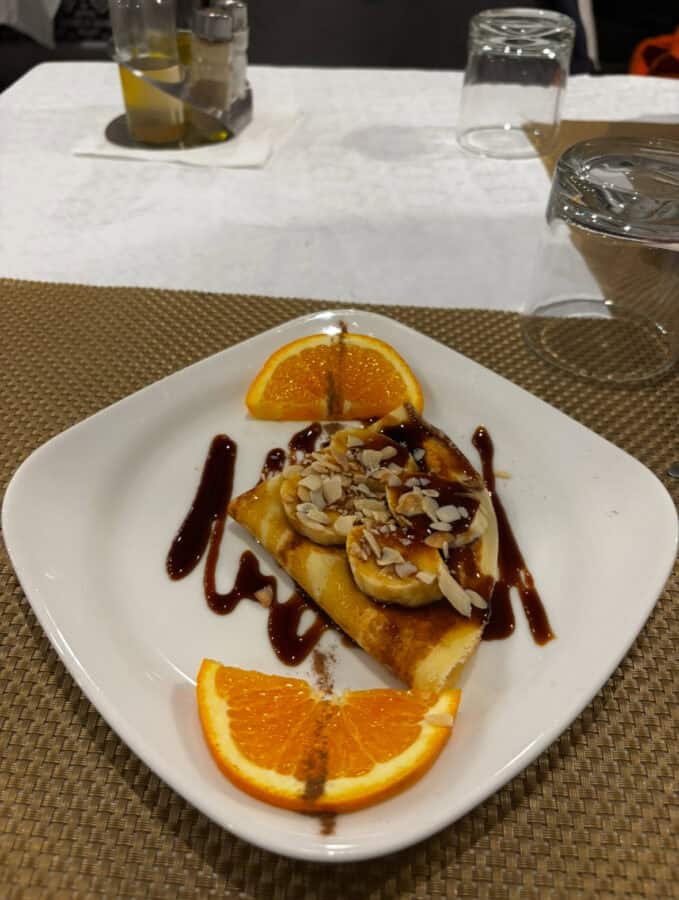 Delicious dessert with fresh fruit, nuts, and rich chocolate drizzle.