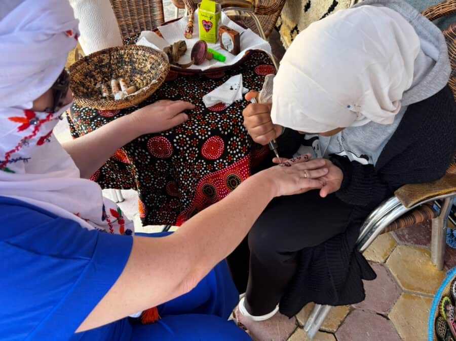 Alt text: Indigenous woman getting a tattoo on her hand by another woman, traditional design seen.