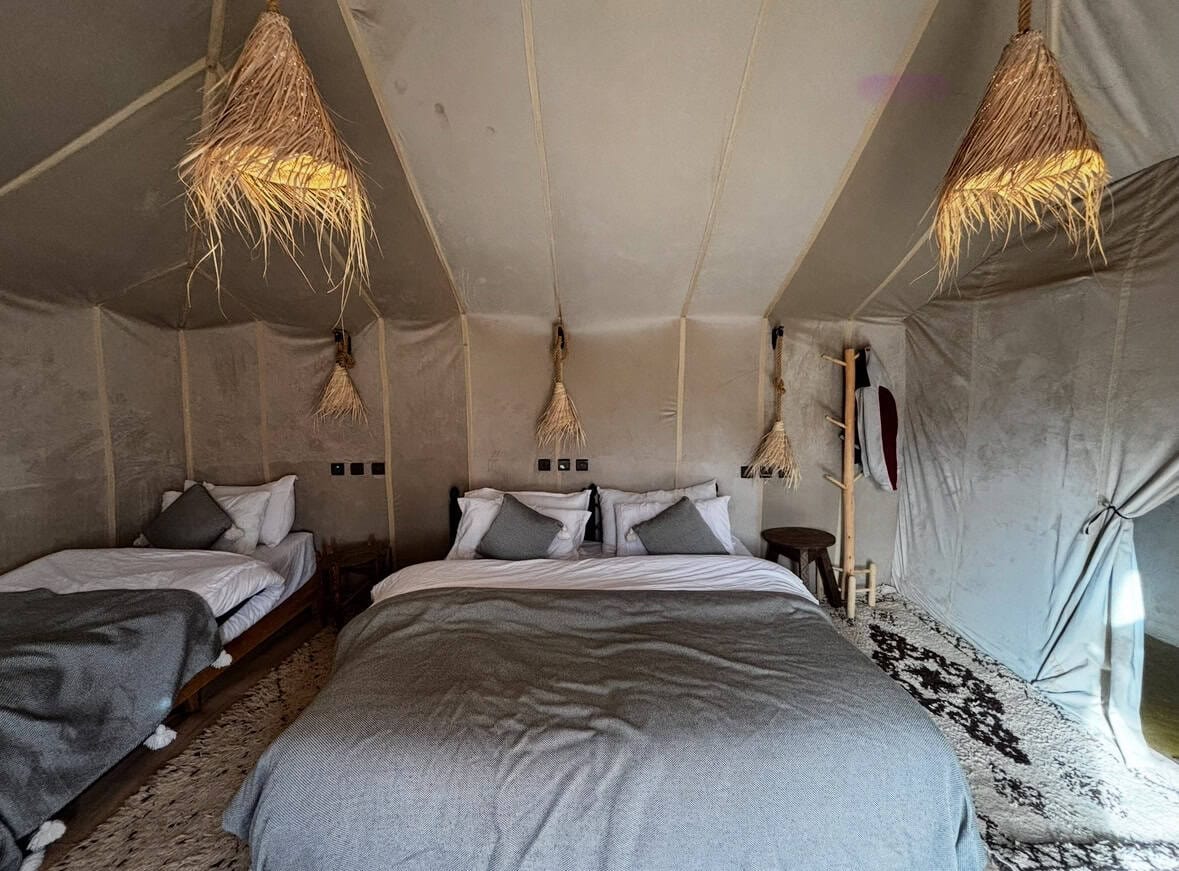 Interior of a rustic glamping tent featuring cozy beds, natural textures, and ambient lighting for outdoor adventure stays.