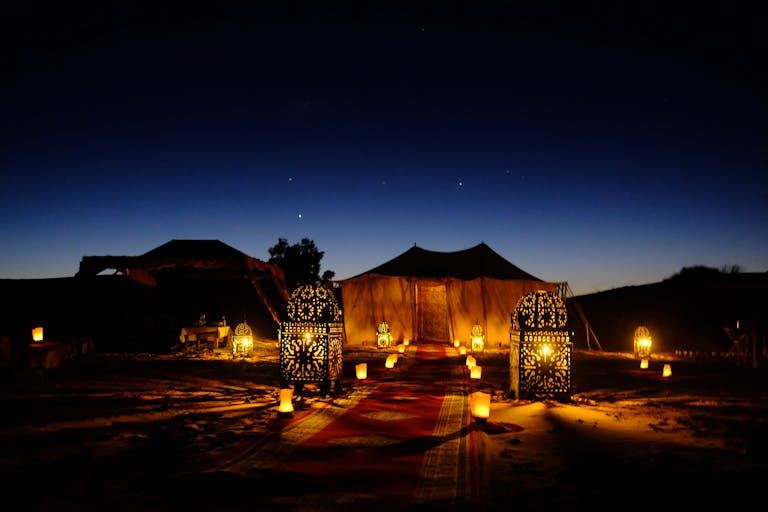 Illuminated tents with lanterns at twilight in Egypt's desert, creating a magical ambiance.