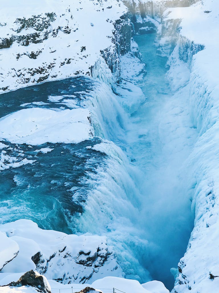 Stunning view of a frozen waterfall cascading through a snowy Icelandic gorge, capturing winter's icy beauty.