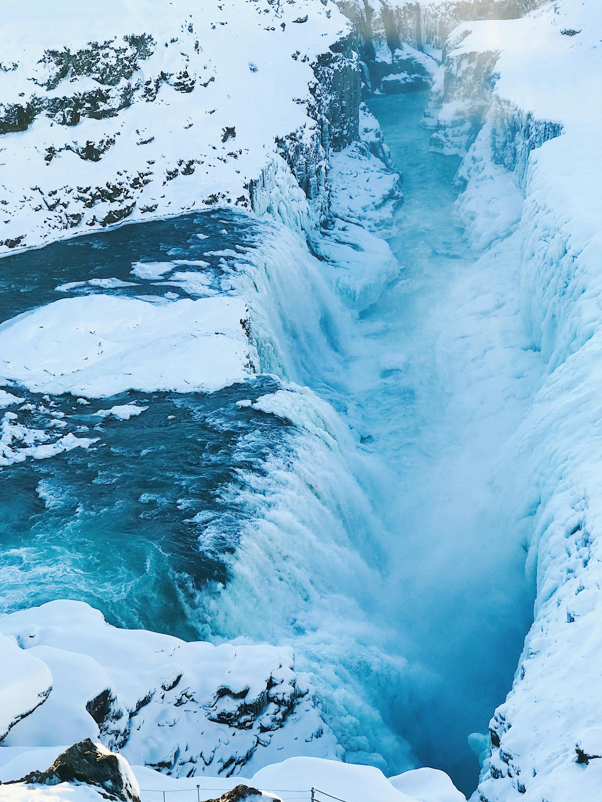 Stunning view of a frozen waterfall cascading through a snowy Icelandic gorge, capturing winter's icy beauty.