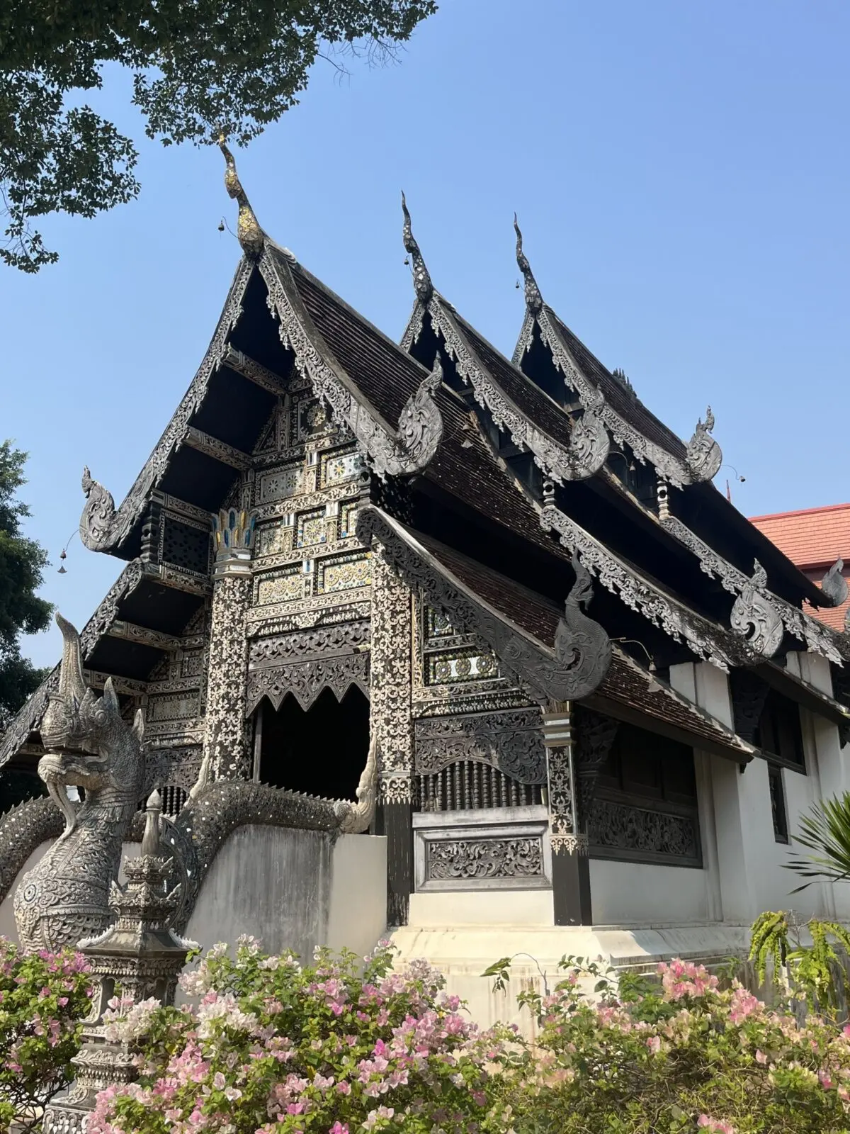 Silver temple against a bright blue sky, with a silver dragon in front of it. 
