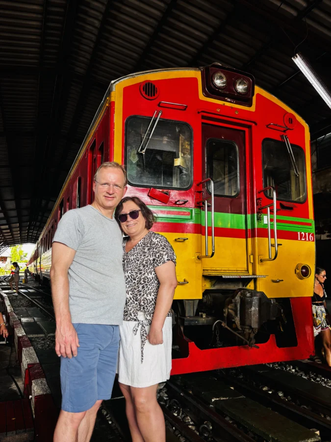 Man and woman posing in front of a train near the train market near Bangkok
