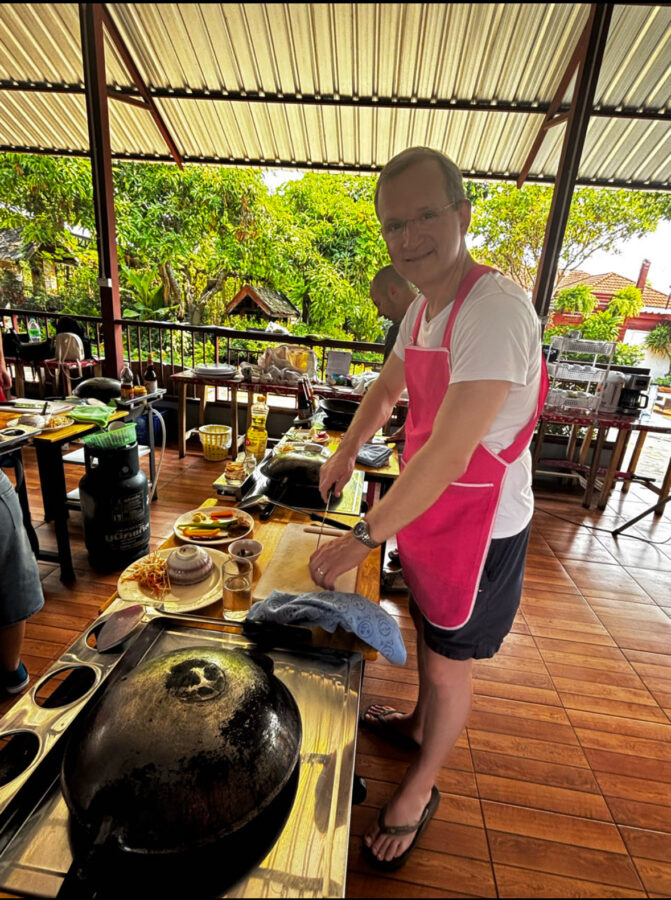 Man standing at a wok in a Chiang Mai cooking class