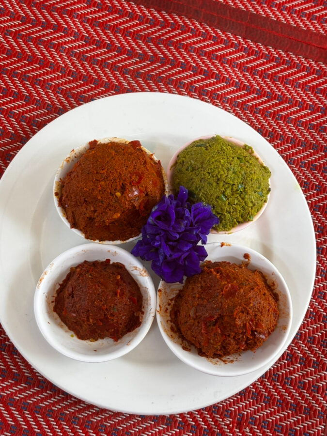 Four curry pastes in vibrant colours, with a purple edible flower. Part of a Thai cooking class
