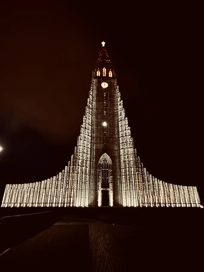 Hallgrimskírkja in Reykjavik in the dark, well lit, seen from the front.