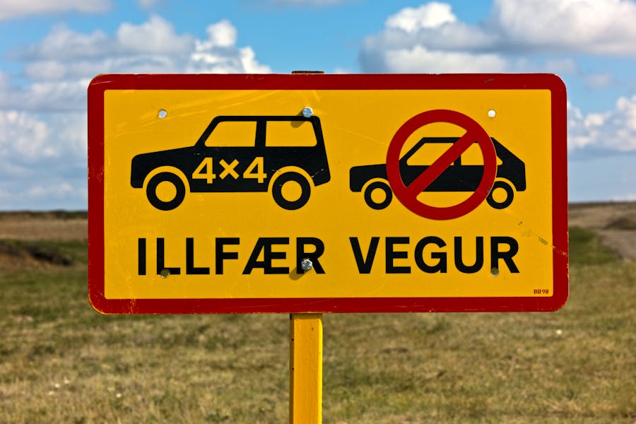 Icelandic road sign prohibiting 2WD vehicles, emphasizing 4x4 use on rural dirt road.
