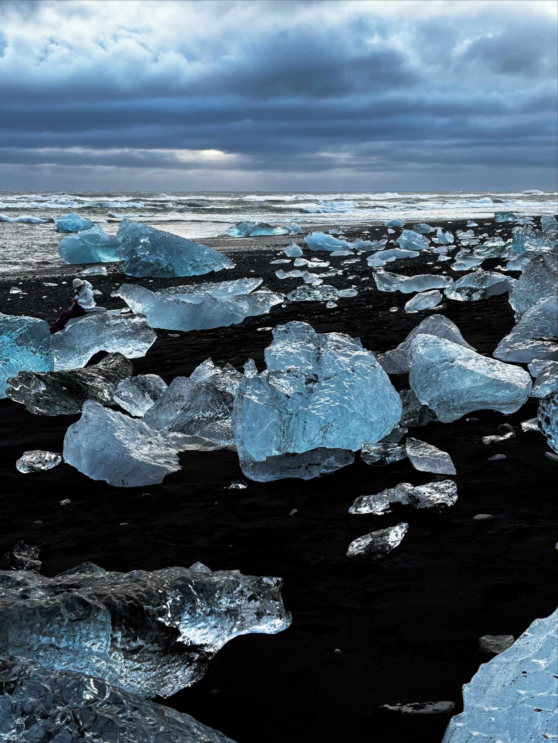 Blue and silvery chunks of ice on black sand, sparkling like diamonds. Diamond Beach, Iceland. Seen after our glacier hike. 