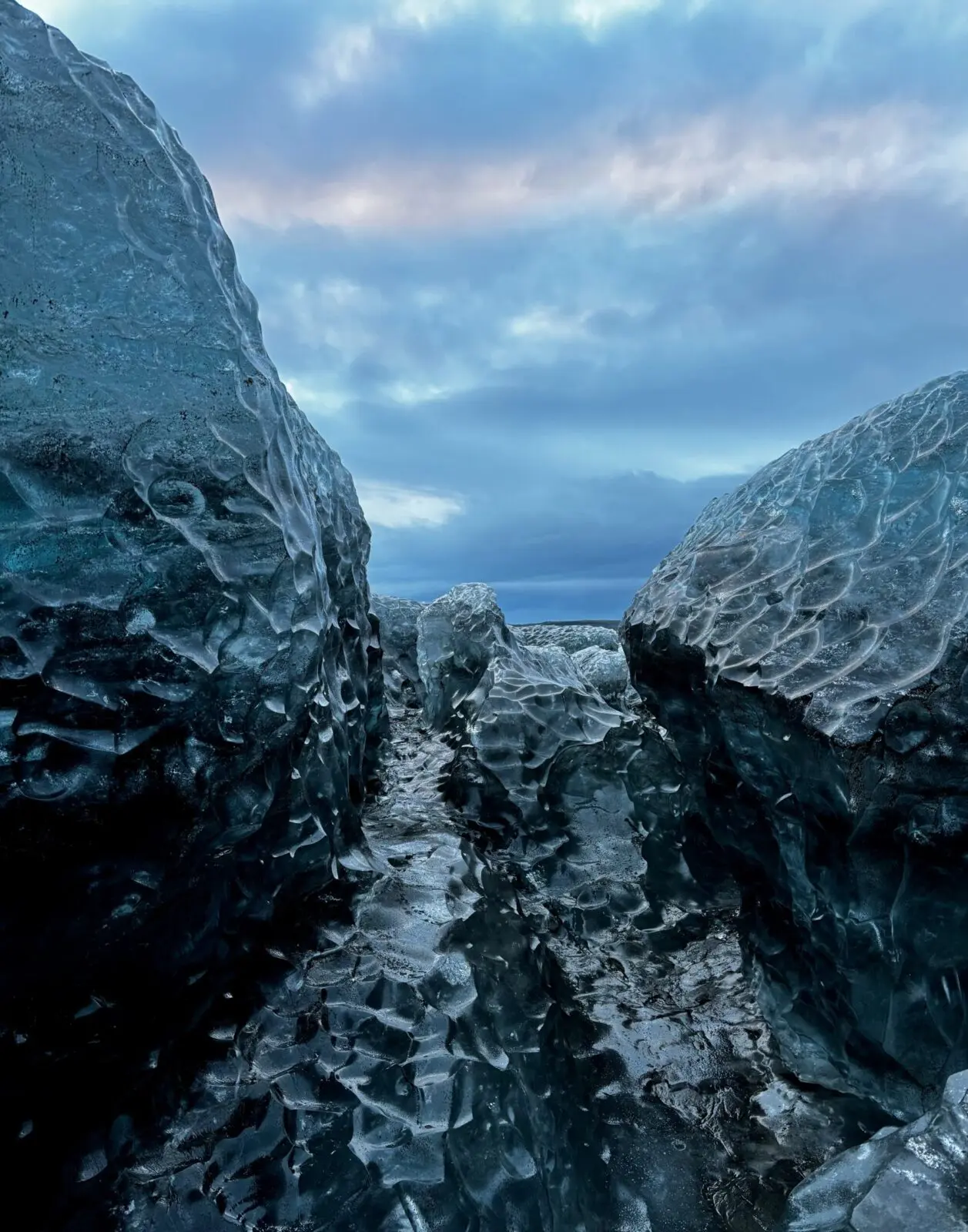 View between two huge chunks of blue ice on Vatnajökull glacier, with a beautiful blue and pink sky