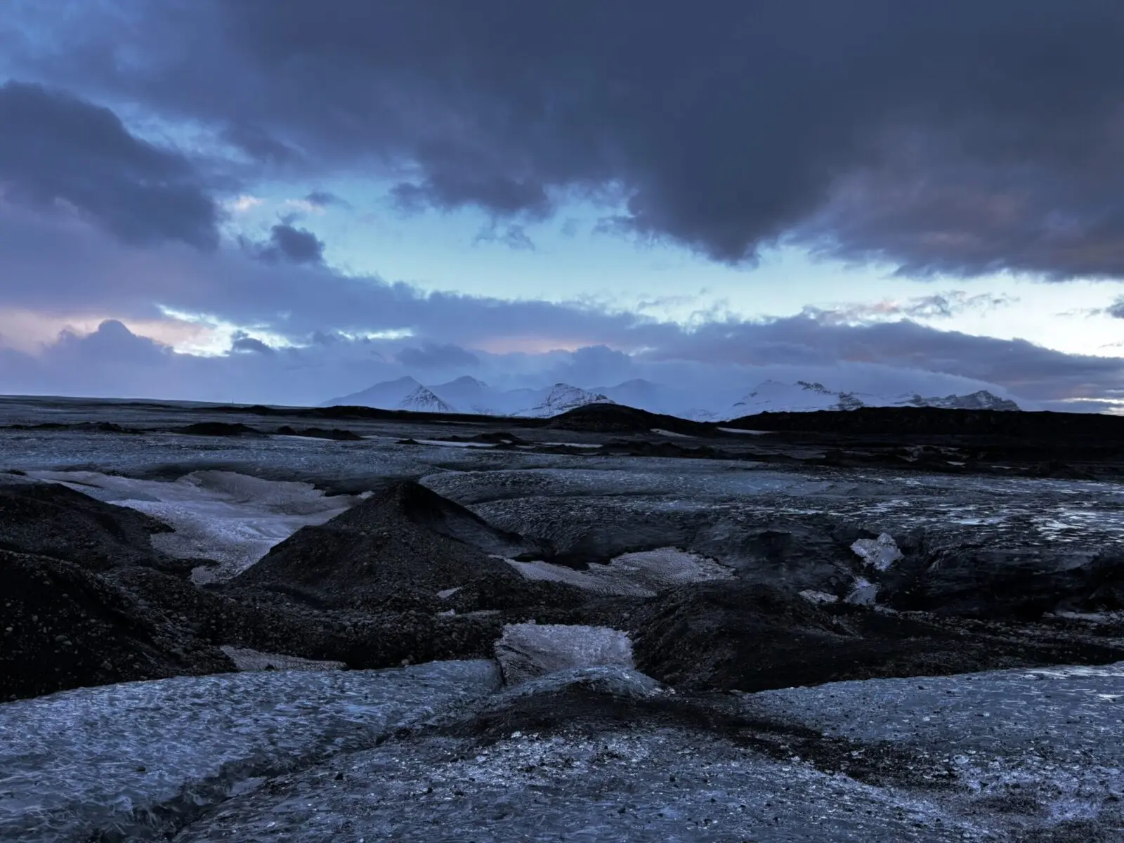 View of blue ice, Vatnajökull glacier and snowy mountains in the distance, early morning.