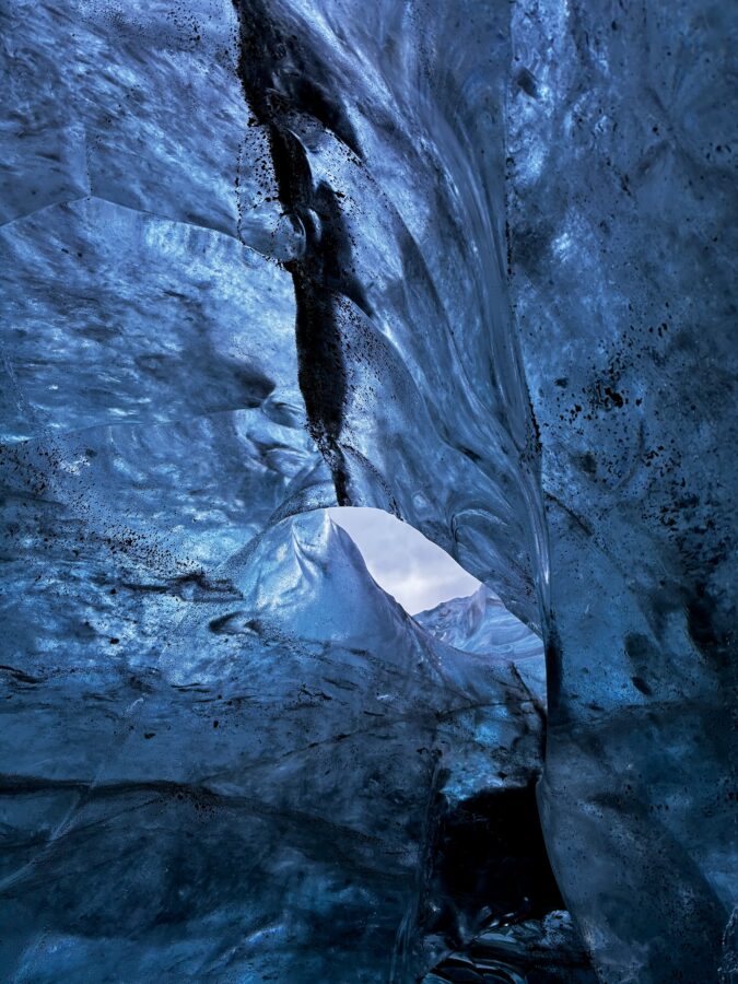 Blue ice up close, with a hole through which the sky is seen