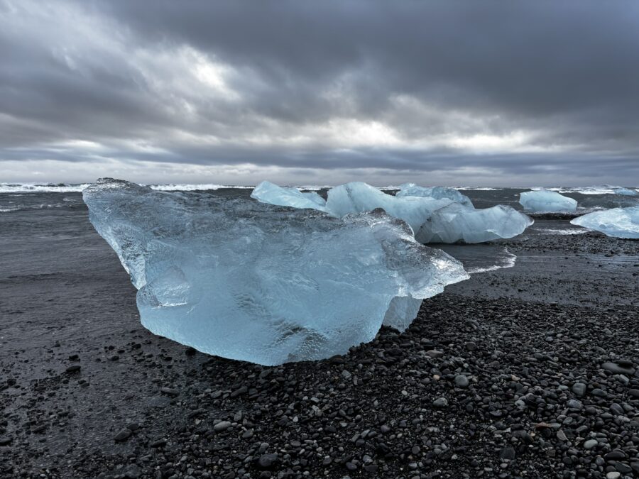 Two big chunks of blue ice on a black sand beach near a glacier in Iceland. Diamond Beach