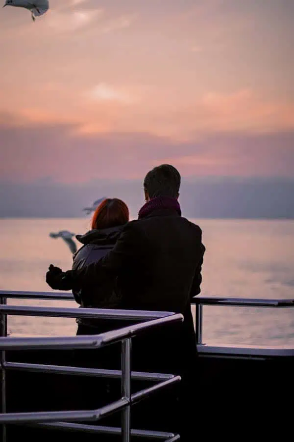 A couple embraces on a cruise ship in Istanbul at sunset, capturing a serene and romantic moment.