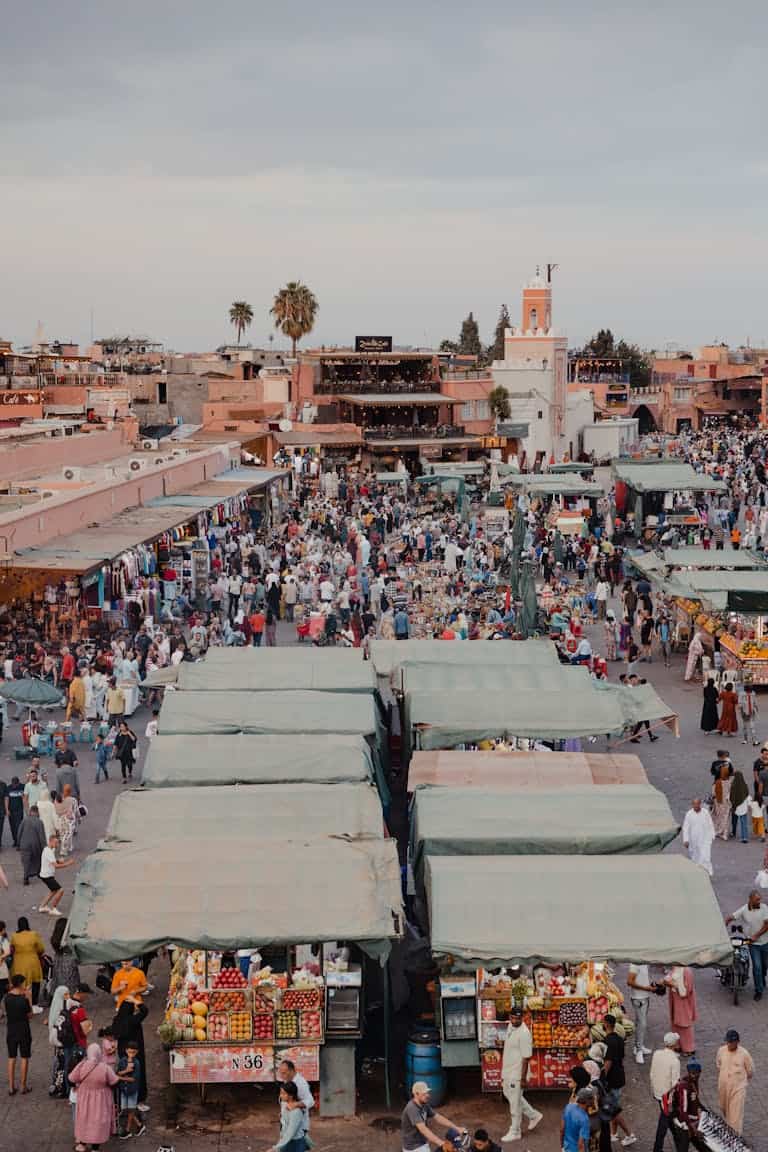 Bustling Moroccan market filled with vendors and shoppers under colourful awnings.