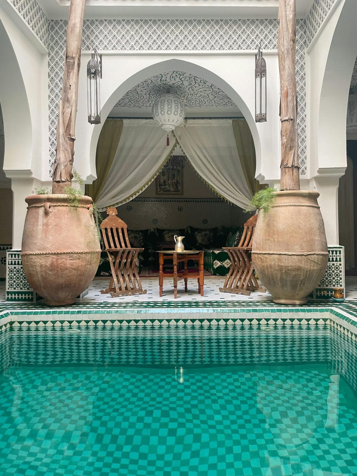 Beautiful Moroccan riad interior with pool, pottery, and luxurious seating in Marrakech.