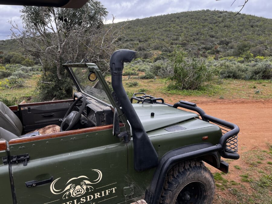 Safari vehicle with logo standing on a dirt road, empty