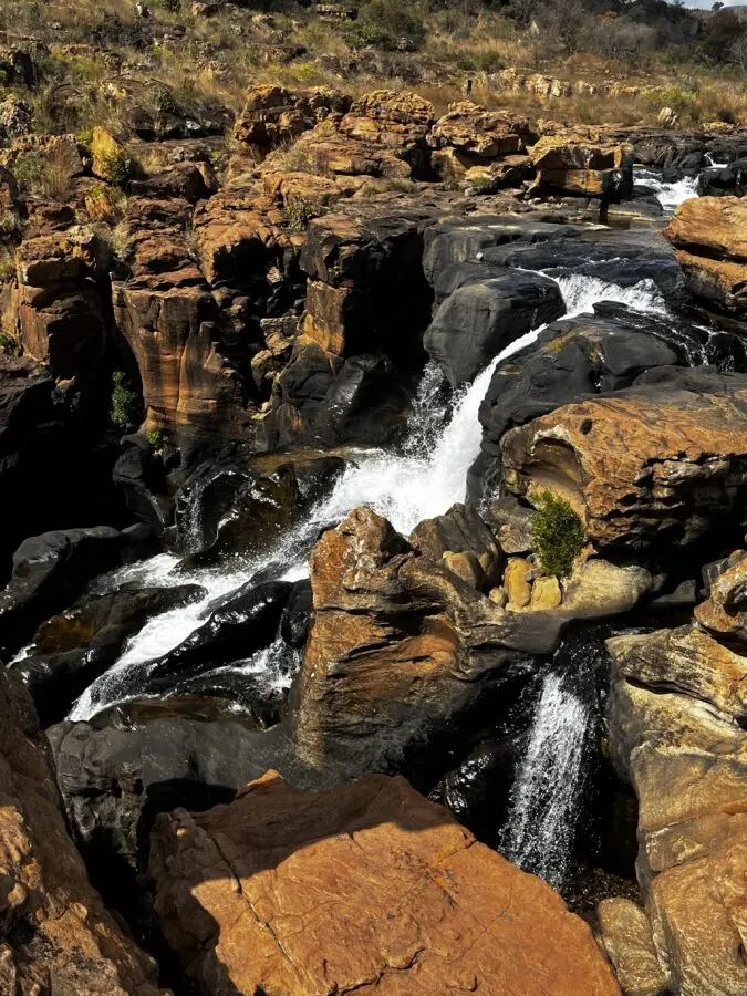 A waterfall falling into a canyon over red and black rocks.