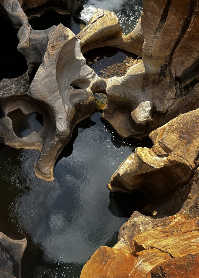 Round holes carved into the rocks by swirling water, seen from above. Coins in the water. Bourke's Luck Potholes