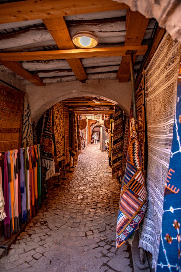 Explore the colorful carpet market in Marrakesh's historic alleyway with traditional Moroccan rugs.