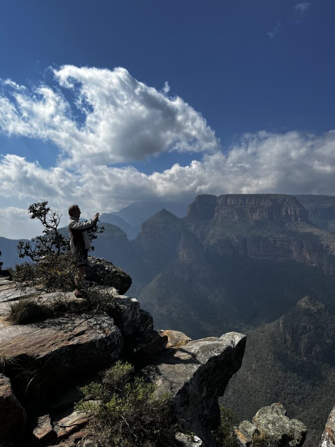 Man standing on a cliff with a view over the Three Rondavels in South Africa. In a post about the question "Is South Africa safe for 55+ travellers?"