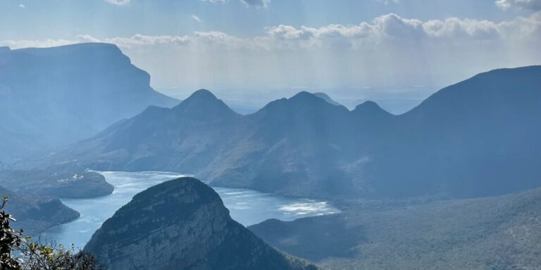 View of a river between mountains, with a haze over the picture. Panorama Route