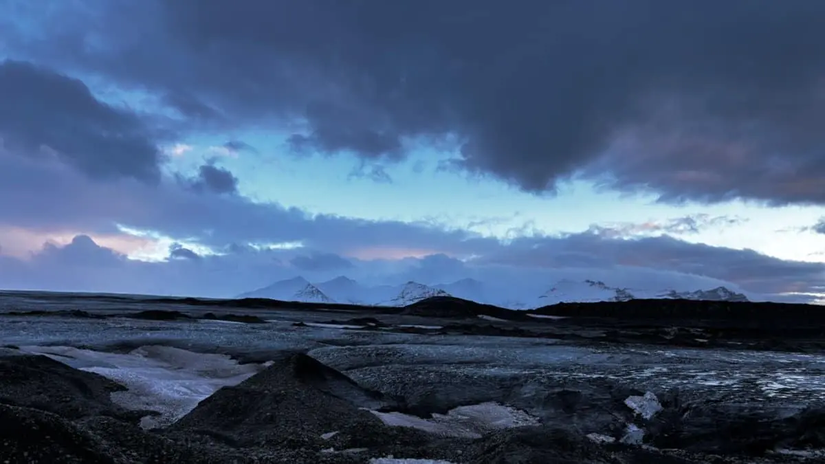 View of Vatnajökull glacier, Iceland. Ice in shades of blue in the foreground, snow-capped mountains in the background