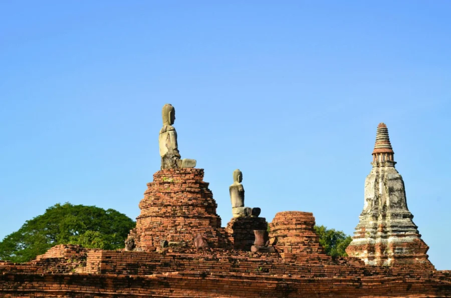 Historic ruins of a Buddhist temple with ancient statues in Ayutthaya, Thailand on a sunny day.