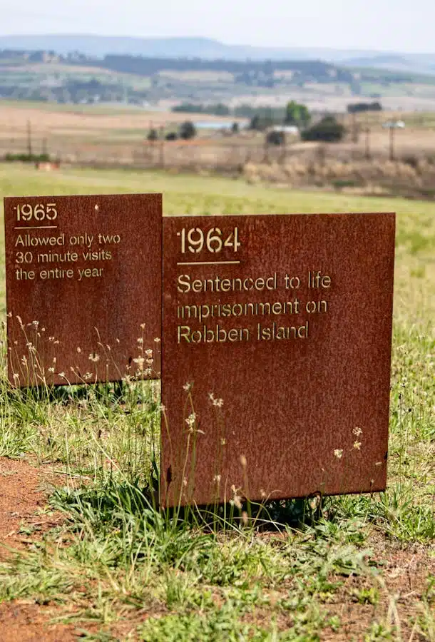 Memorial plaques at Robben Island commemorate significant historic events in a rural setting.