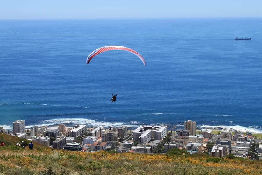 Paraglider soaring above Cape Town with a breathtaking ocean view, showcasing the vibrant city below.