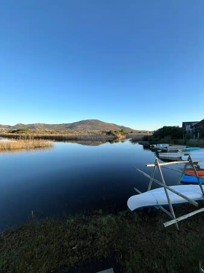 Tranquil morning scene of Lake Michelle in Cape Town, showcasing calm waters and distant mountains.