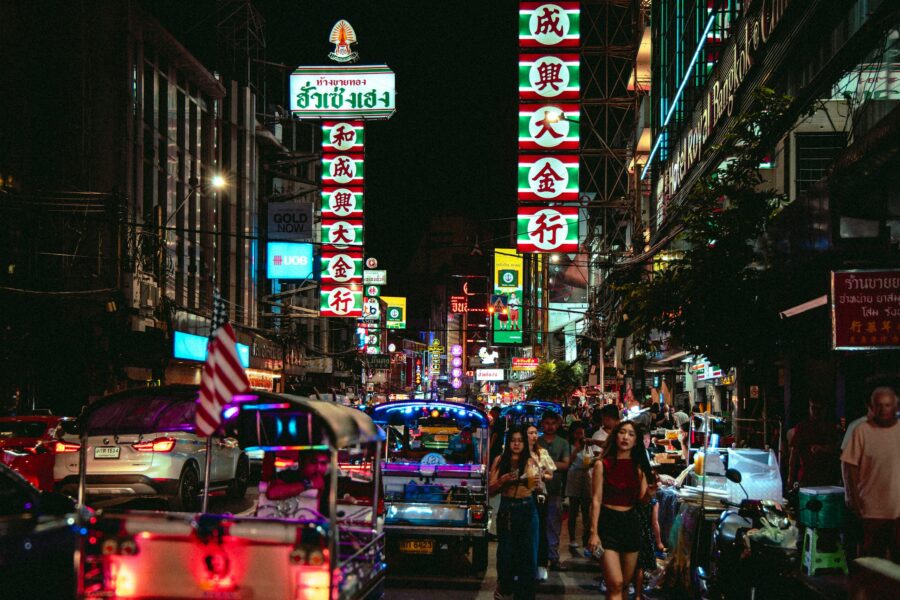 Vibrant night scene in Bangkok's Chinatown with tuk-tuks and neon lights.