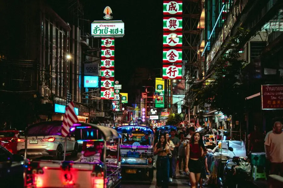 Vibrant night scene in Bangkok's Chinatown with tuk-tuks and neon lights.