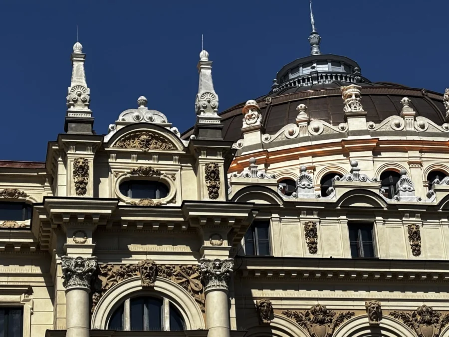 Photo: Tales From The Road Ahead.  Shot of a richly decorated building in Kraków, Poland. Turrets, statues, windows, sandstone against a bright blue sky. 