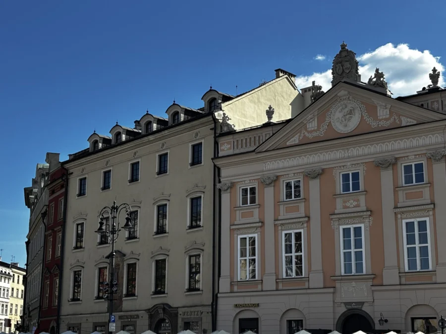 Photo: Tales From The Road Ahead. Buildings on the main square (Rynek Główny) in Kraków. Bright blue sky.