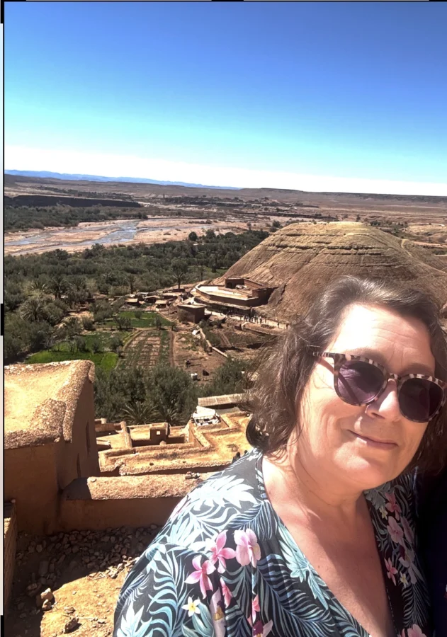Travel blog writer Alexandra, 57, at the old fort at Ait Ben Haddou, Morocco. Terracotta-coloured stone, a nearly dry river bed down below. Travel worries temporarily forgotten. 