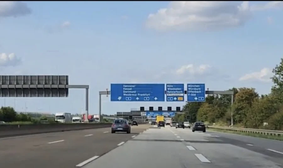 View of road signs on a German motorway with a few cars driving on the road. Seen through the windscreen of a car by travel blog writer Alexandra (Tales from the road ahead)who had just realised she'd left her passport at home and it was much too far to turn back. 