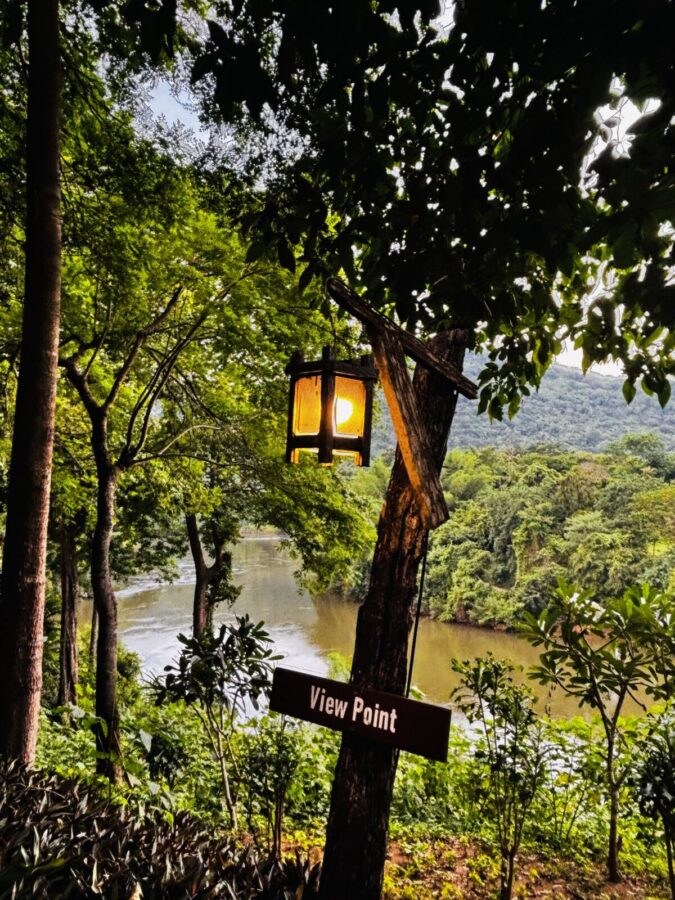 View from high on a hill over River Kwai at sunset, with a lantern in a tree and a sign saying view point