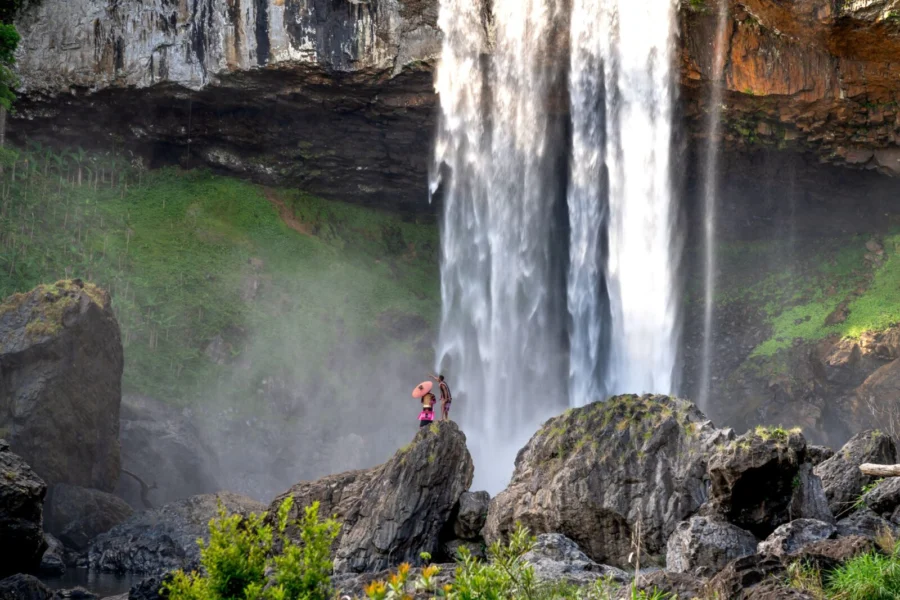 A picturesque waterfall cascading down a rocky cliff, with visitors exploring the scenic view.
