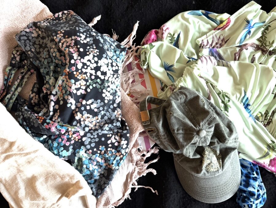 A messy pile of clothing, a hat, a bath towel, all ready to be packed for Indonesia. 